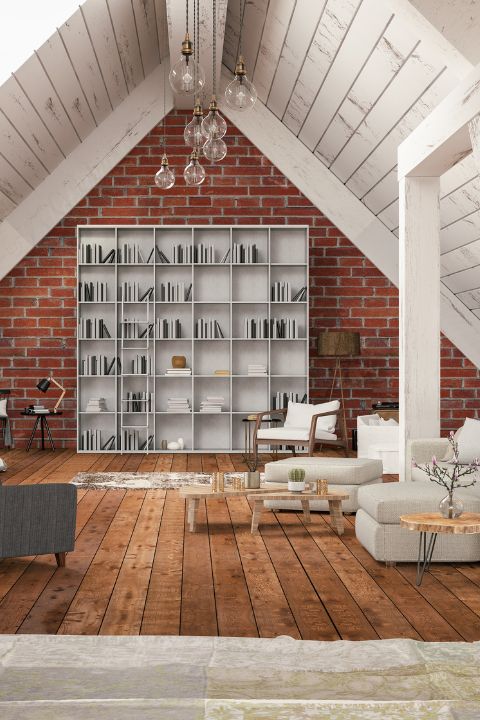 Interno mansarda con pareti in mattoni a vista, libreria moderna integrata e pavimenti in legno chiaro.