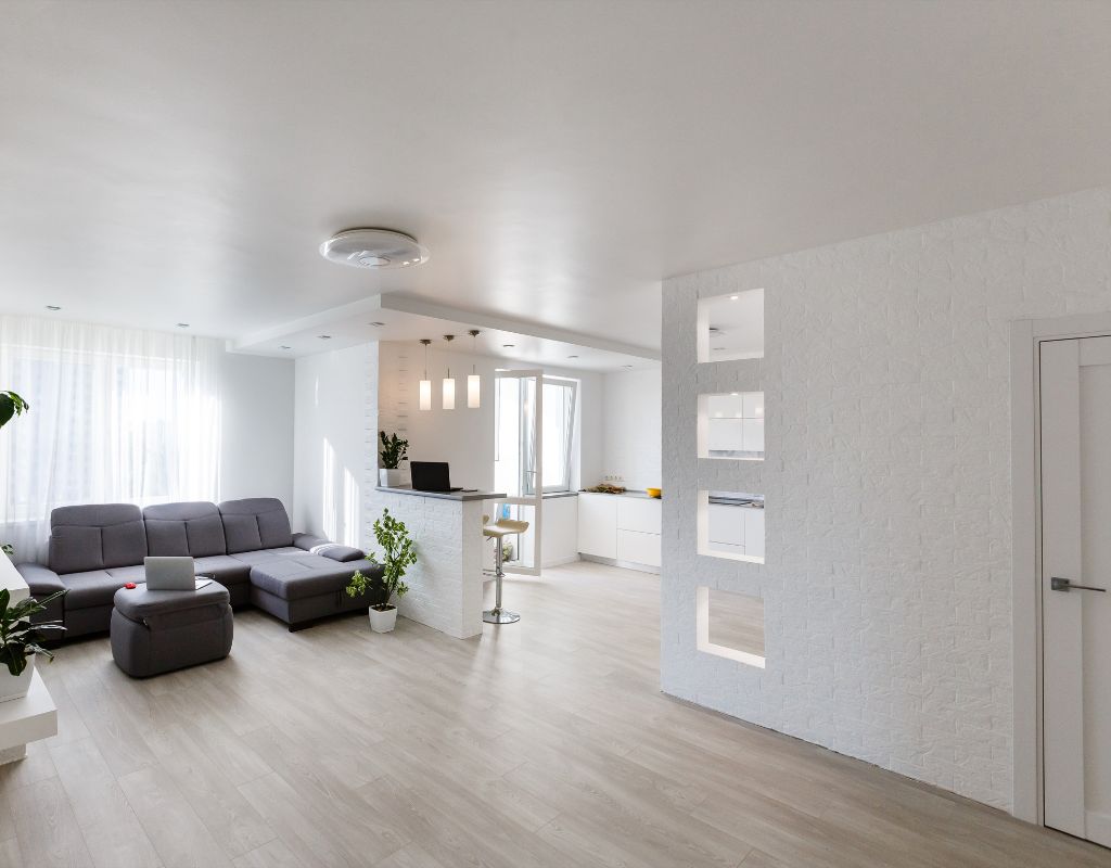 Soggiorno moderno ristrutturato con divano grigio, parete testurizzata e illuminazione a sospensione